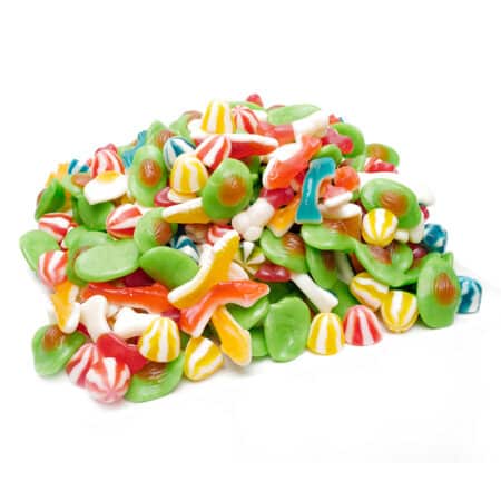Fruchtgummimischung in Großaufnahme: Herzförmige, blaue, rote und gelbe Gummis, umgeben von Zucker.