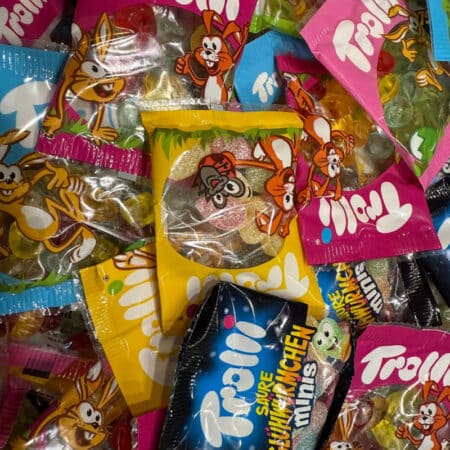 Bunte, glänzende Trolli Fruchtgummis in der Tüte. Verschiedene Farben und Formen von oben gesehen.