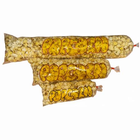 Süßes Popcorn in einer rot-weiß gestreiften Papiertüte vor unscharfem Hintergrund.