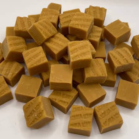 Weiche Lonka-Vanille-Fudge-Stücke in Nahaufnahme, von oben fotografiert, auf Holzoberfläche.