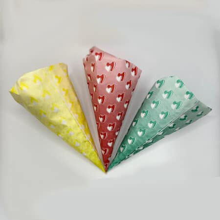 Spitztüten aus Papier in drei verschiedenen Größen, weiß mit dünnen roten Streifen und einem roten Rand.
